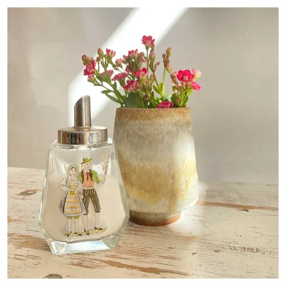 Ein Zuckerstreuer und eine Keramikvase mit rosa Blüten auf einem hellen Tisch