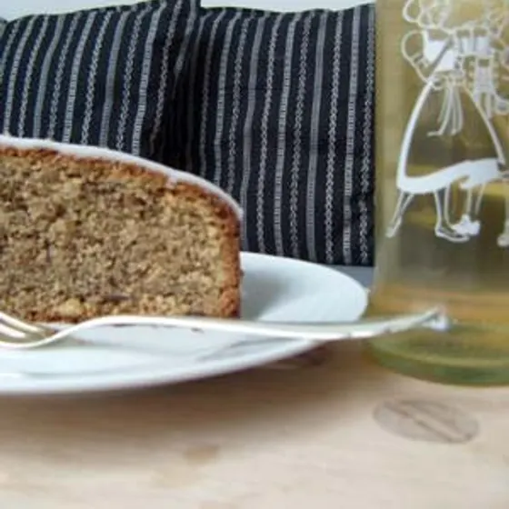 Ein Stück Nusskuchen auf einem weißen Teller vor blau gestreiften Kissen