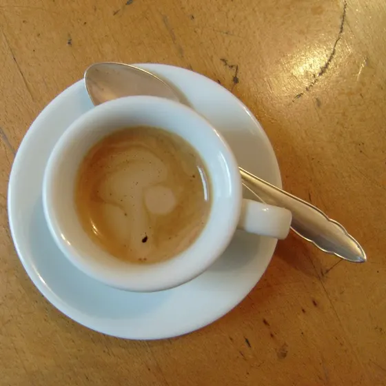 Eine ausgetrunkene Espressotasse mit Löffel auf einem Holztisch