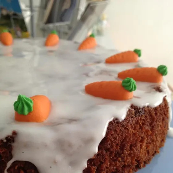 Ein Karottenkuchen mit weißem Zuckerguss und kleinen Marzipanmöhren
